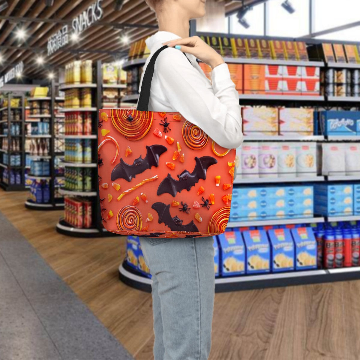 Sac fourre-tout Halloween avec motifs de chauves-souris et bonbons, porté par une personne en magasin.