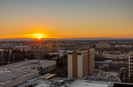 the sun is setting over a city with tall buildings